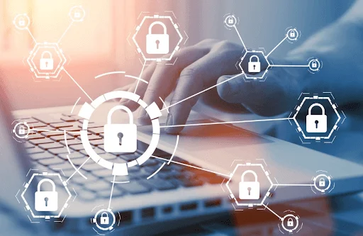 Imagem de uma mão mexendo em um notebook e vários ícones de cadeados em cima.