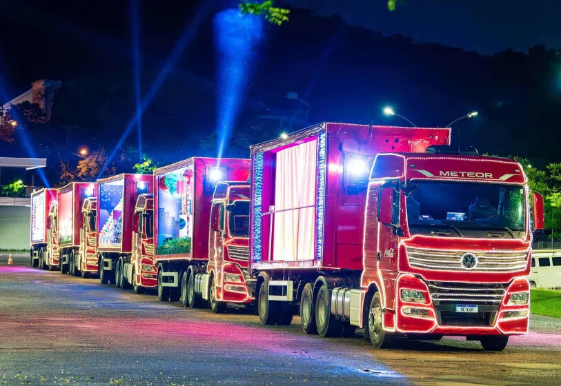 Foto de cinco caminhões decorados para a campanha da Caravana de Natal da Coca-Cola.