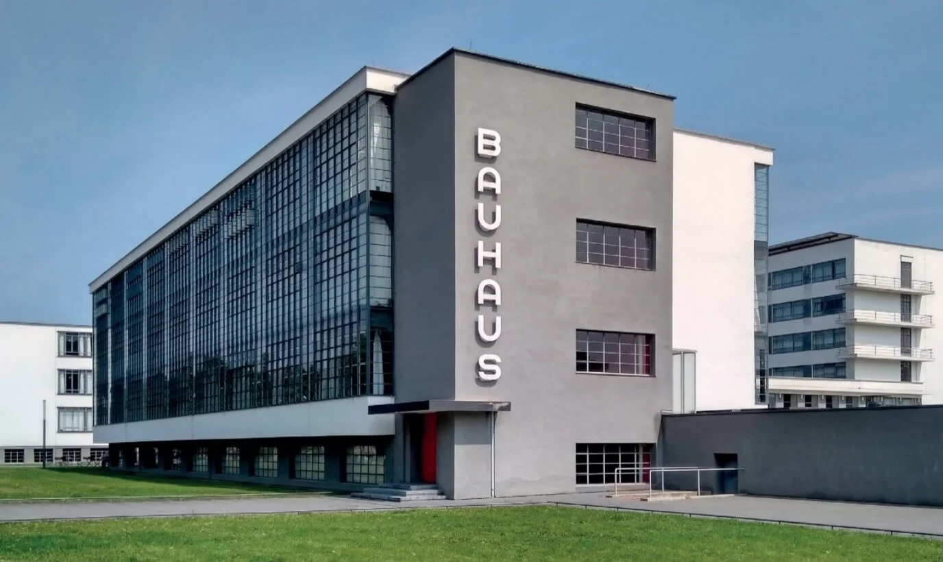 Foto de um edifício com linhas retas, fachada envidraçada e o letreiro “Bauhaus” na lateral cinza.