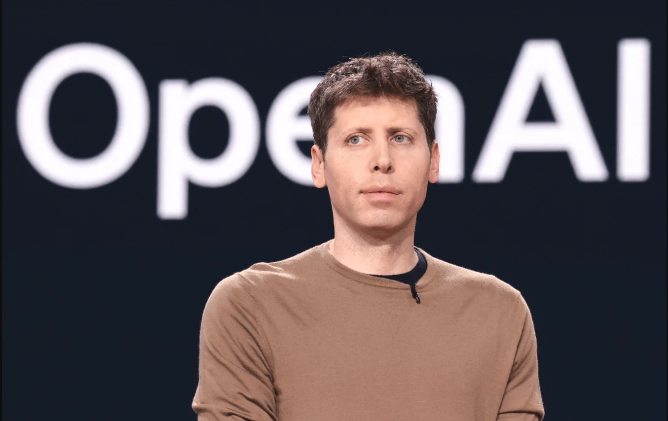 Sam Altman, CEO da OpenAI, na frente de um fundo preto onde está escrito, em branco, “OpenAI”