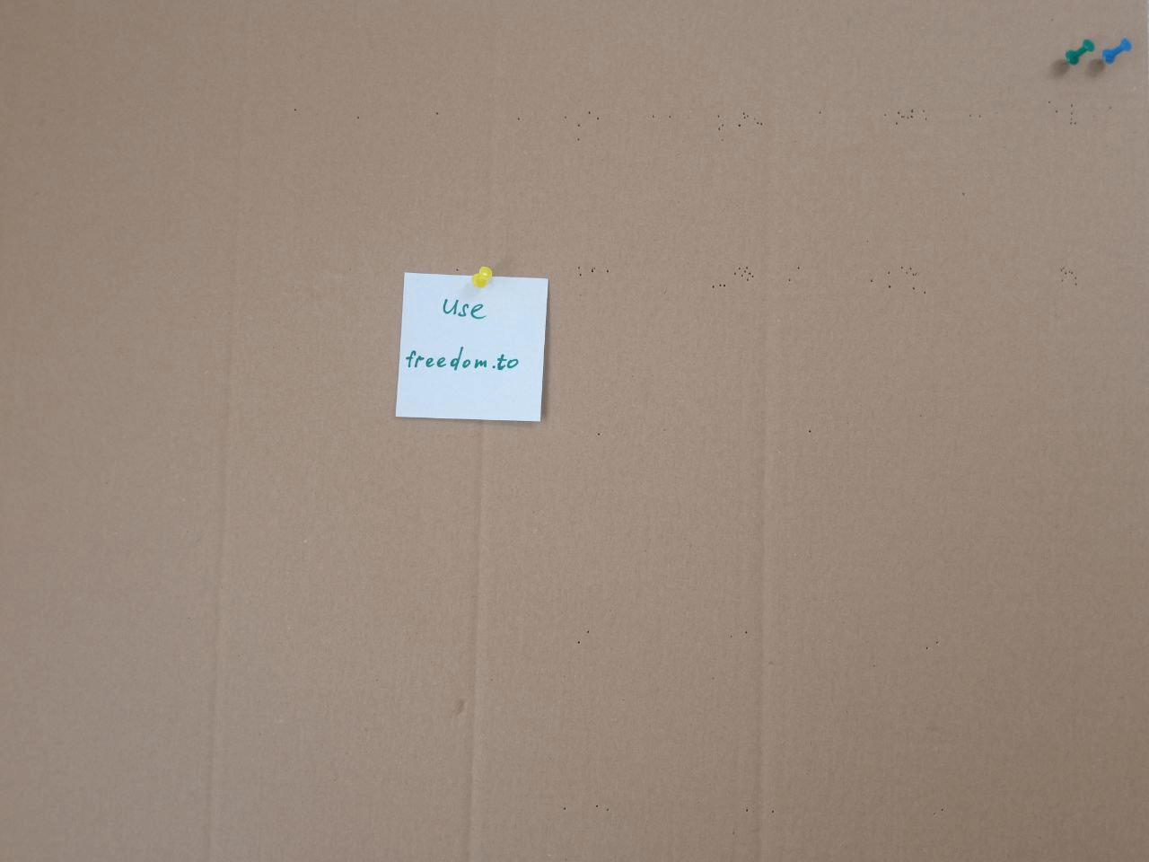 A sticky note pinned to a piece of cardboard that says “Use freedom.to”