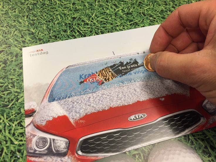 A picture of a promotional flyer from Kia with a person’s hand scratching it off with a coin