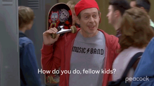 Steve Buscemi wearing a T-shirt that says “Music band” imitating the AC/DC logo, carrying a skateboard, close captions says: “How do you do, fellow kids?”